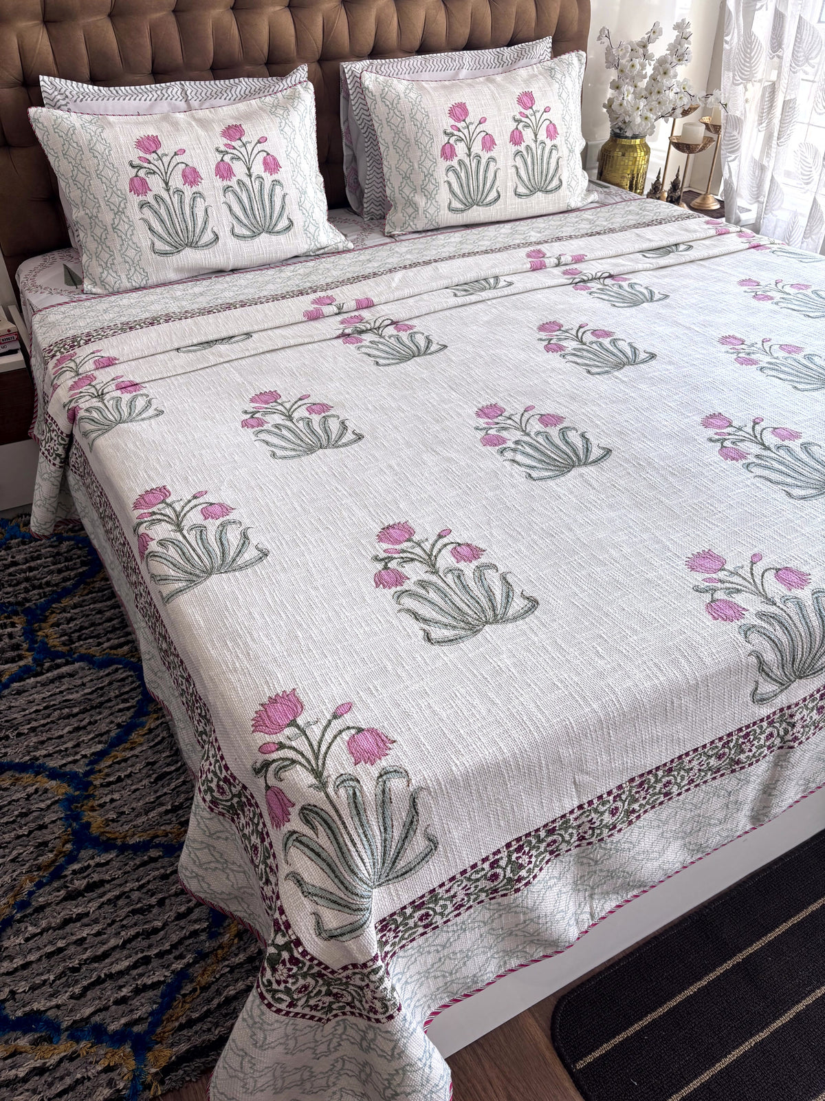 Full view of Gulmohar Melody king size jute cotton bedcover featuring pink floral hand block print and Jaipuri border.