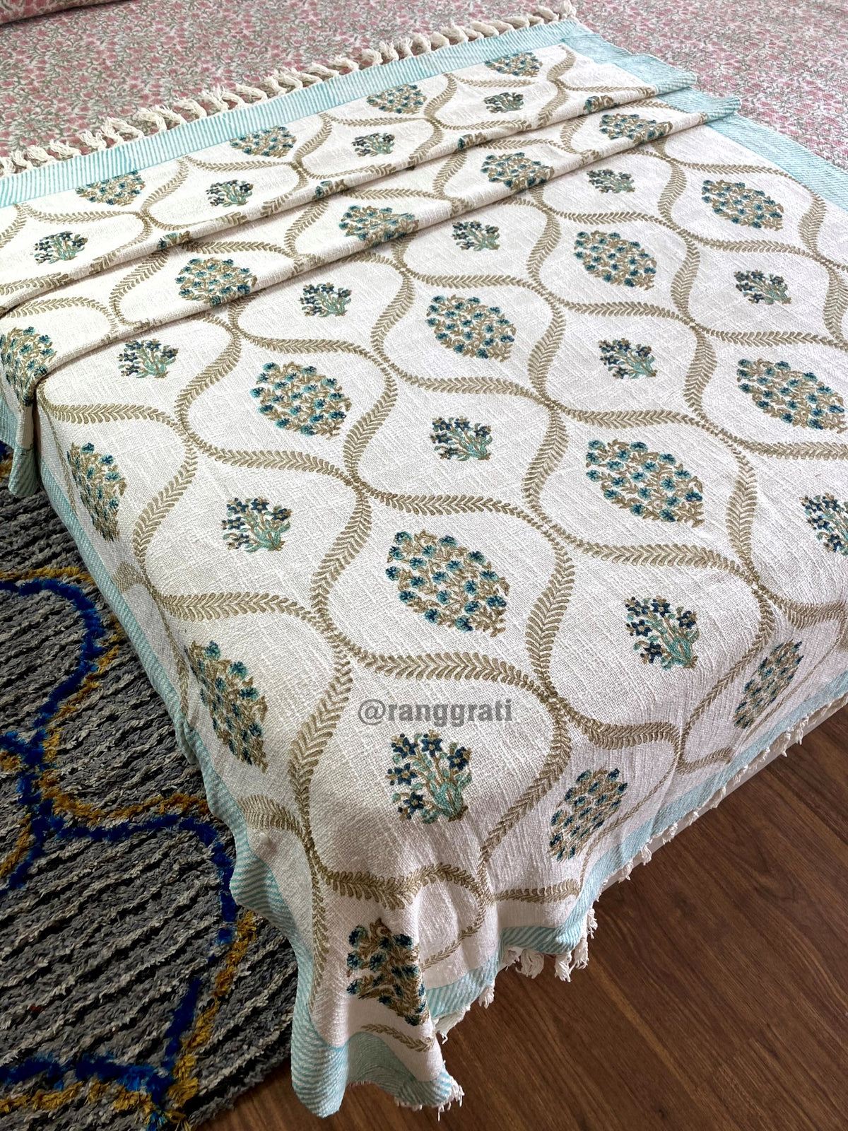 Turquoise Floral Hand Block Jute Cotton Sofa Throw - on bed, side view